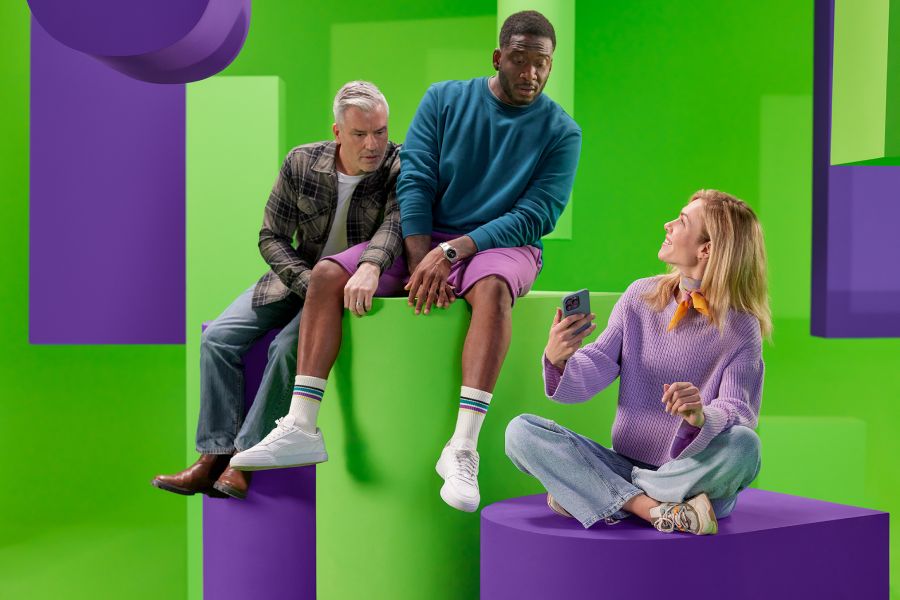 2 mannen en 1 vrouw vergelijken zittend hun energieverbruik op mobiele telefoon.