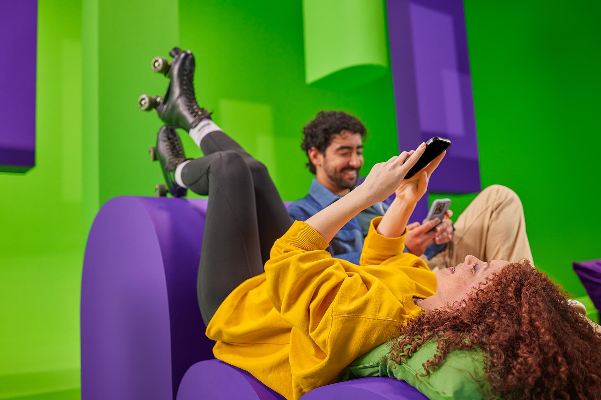 Man en vrouw op een bank lezen ieder op hun telefoon het nieuws van energiedirect