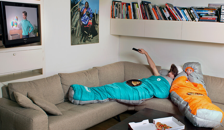 Twee mensen op de bank, beiden in een slaapzak
